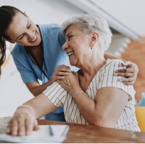 Une aide à domicile souriante réconforte une dame âgée